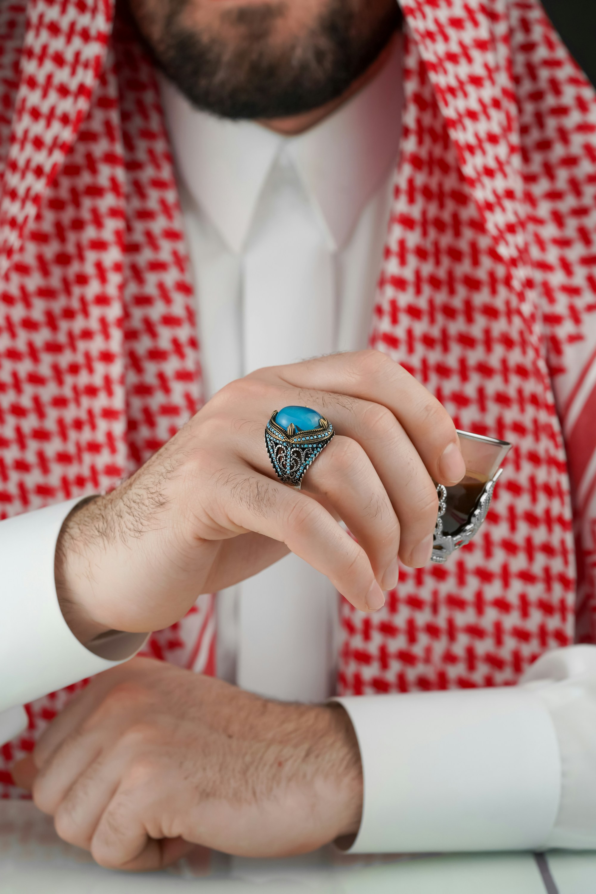 Turquoise ring, Arabic coffee, and the cuff of a white thobe