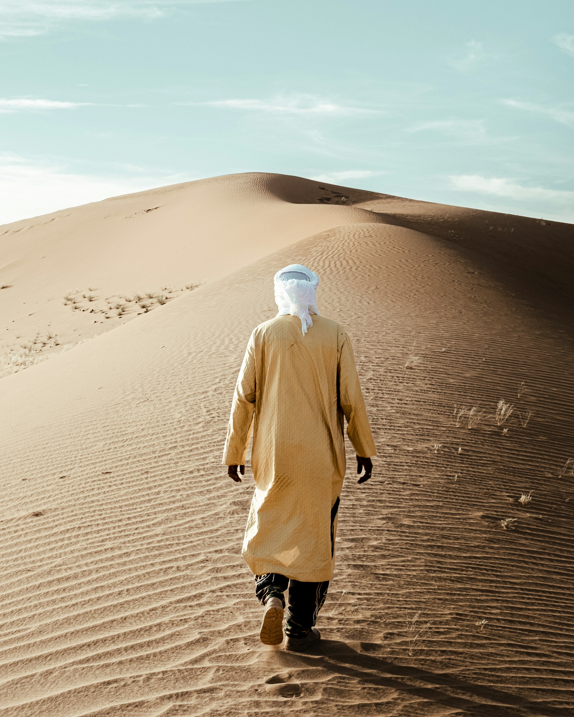 Camel-tan robe moving across a ridged dune